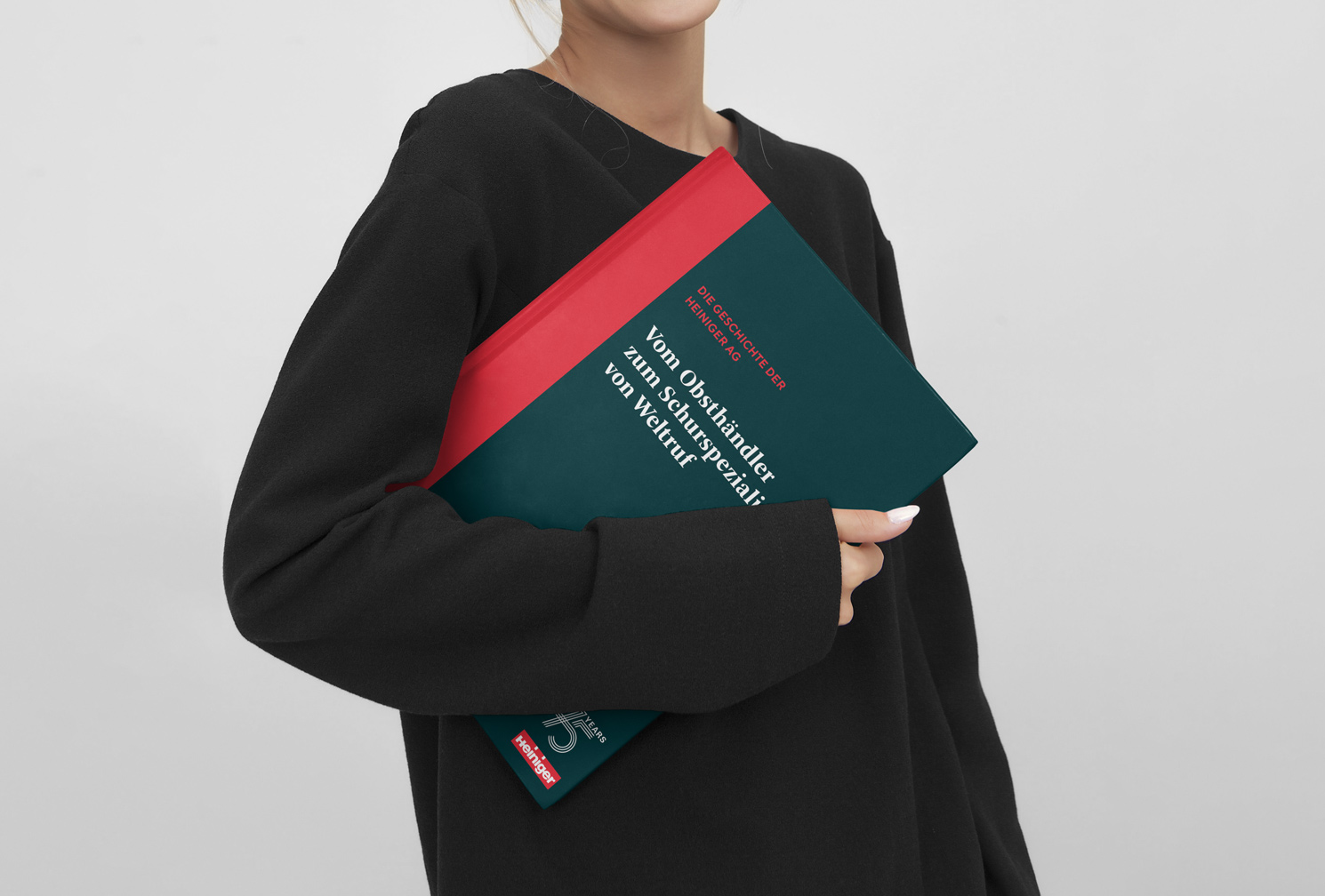 Heiniger AG, Frau hält Jubiläumsbuch unter dem Arm, Editorial Design